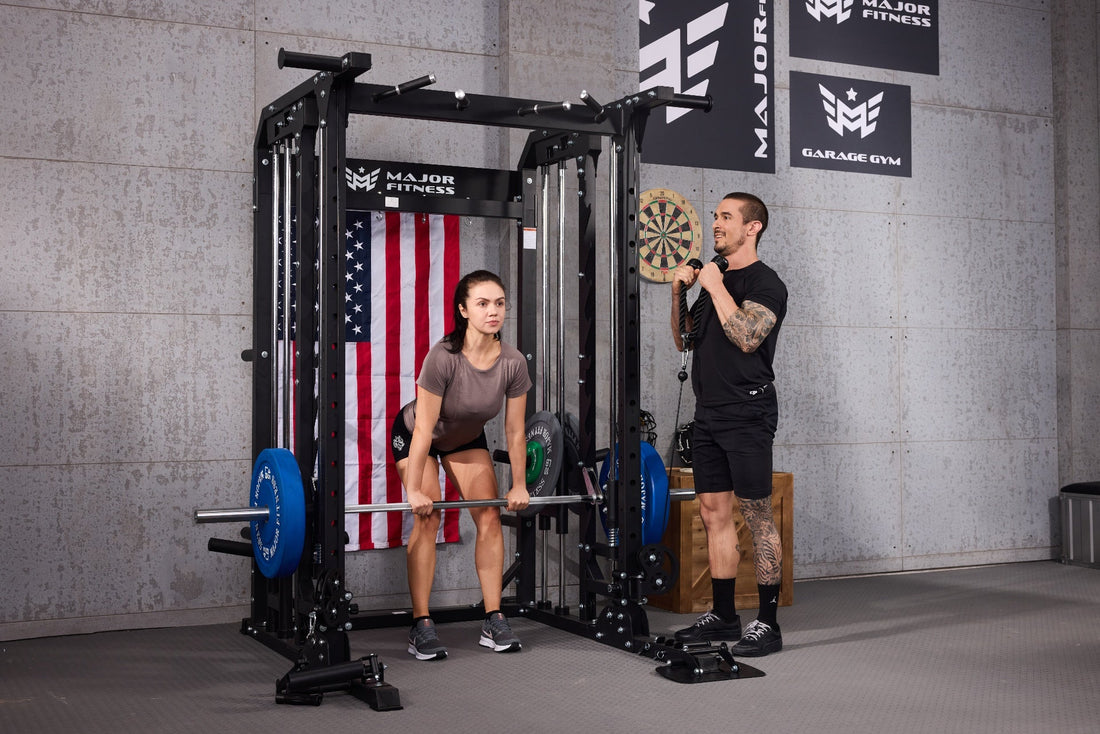 Female doing a deadlift and male doing cable exercises with Major Lutie Smith machine in a fitness room.