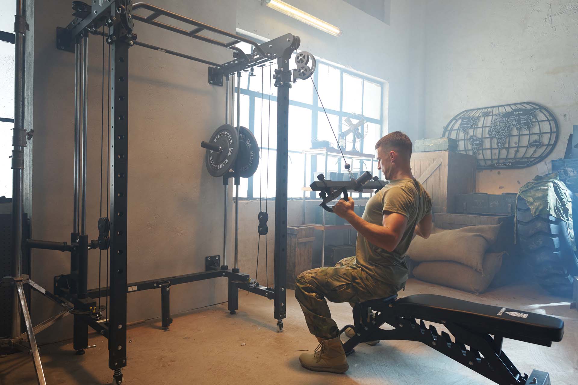 A uniformed man doing lat-pulldown on power rack