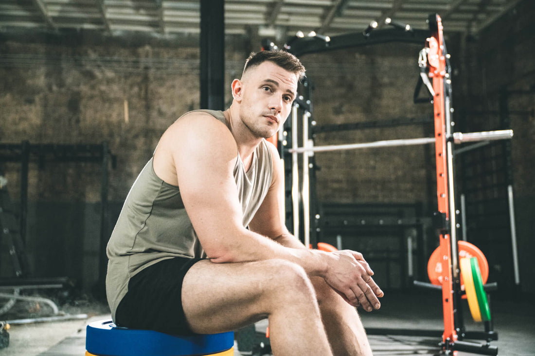 man seated on a plyo box in the gym, resting after a workout session