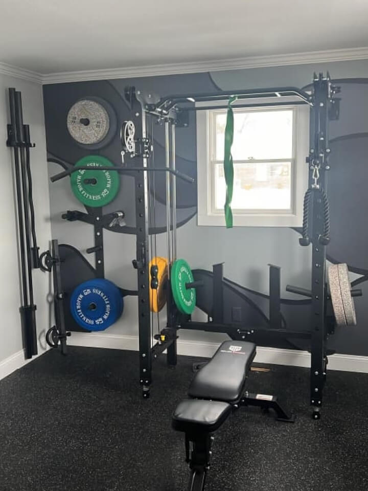 Indoor gym with bench and black folding power rack, colored weight plates