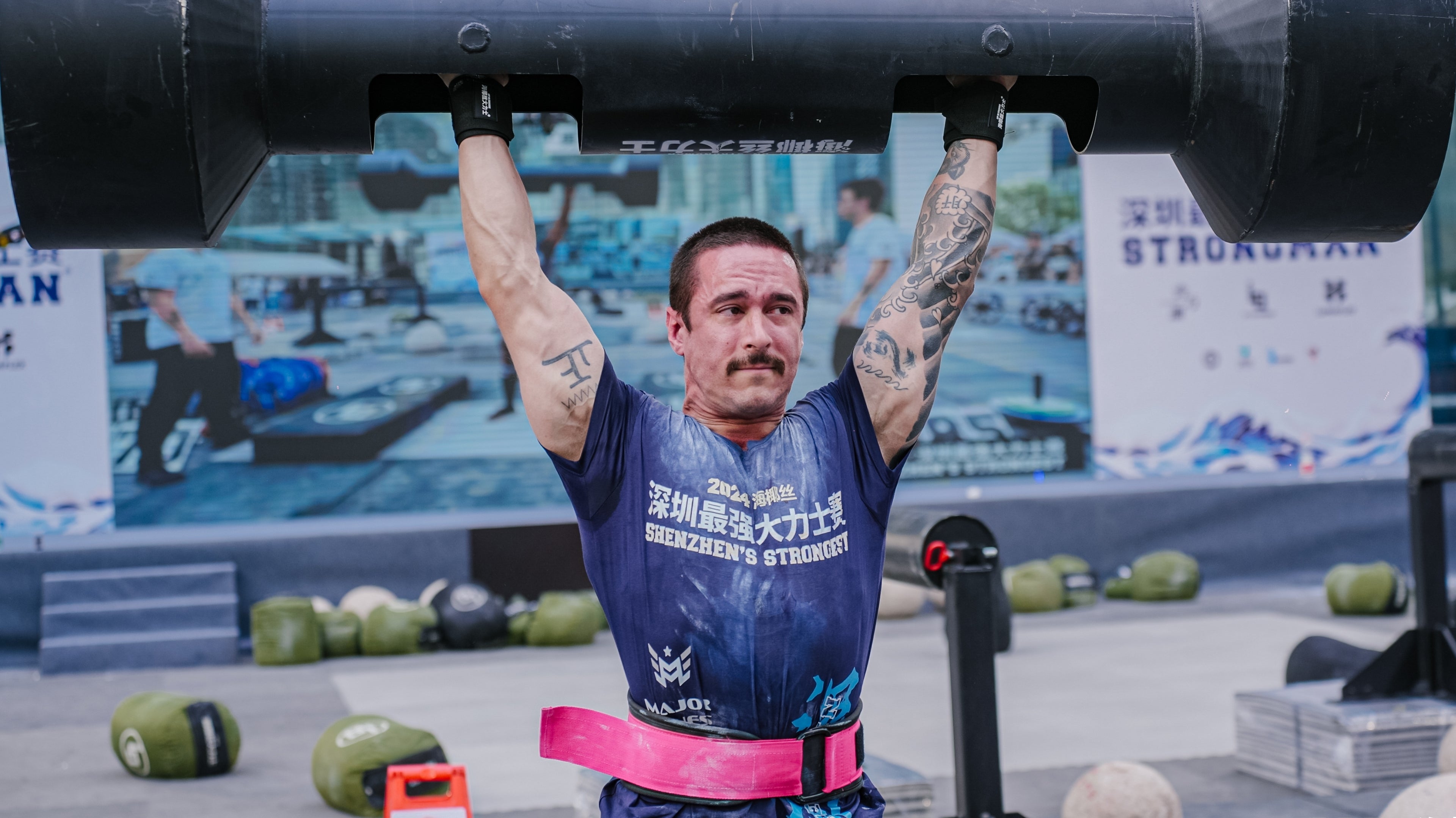 A focused male athlete lifting a heavy log overhead