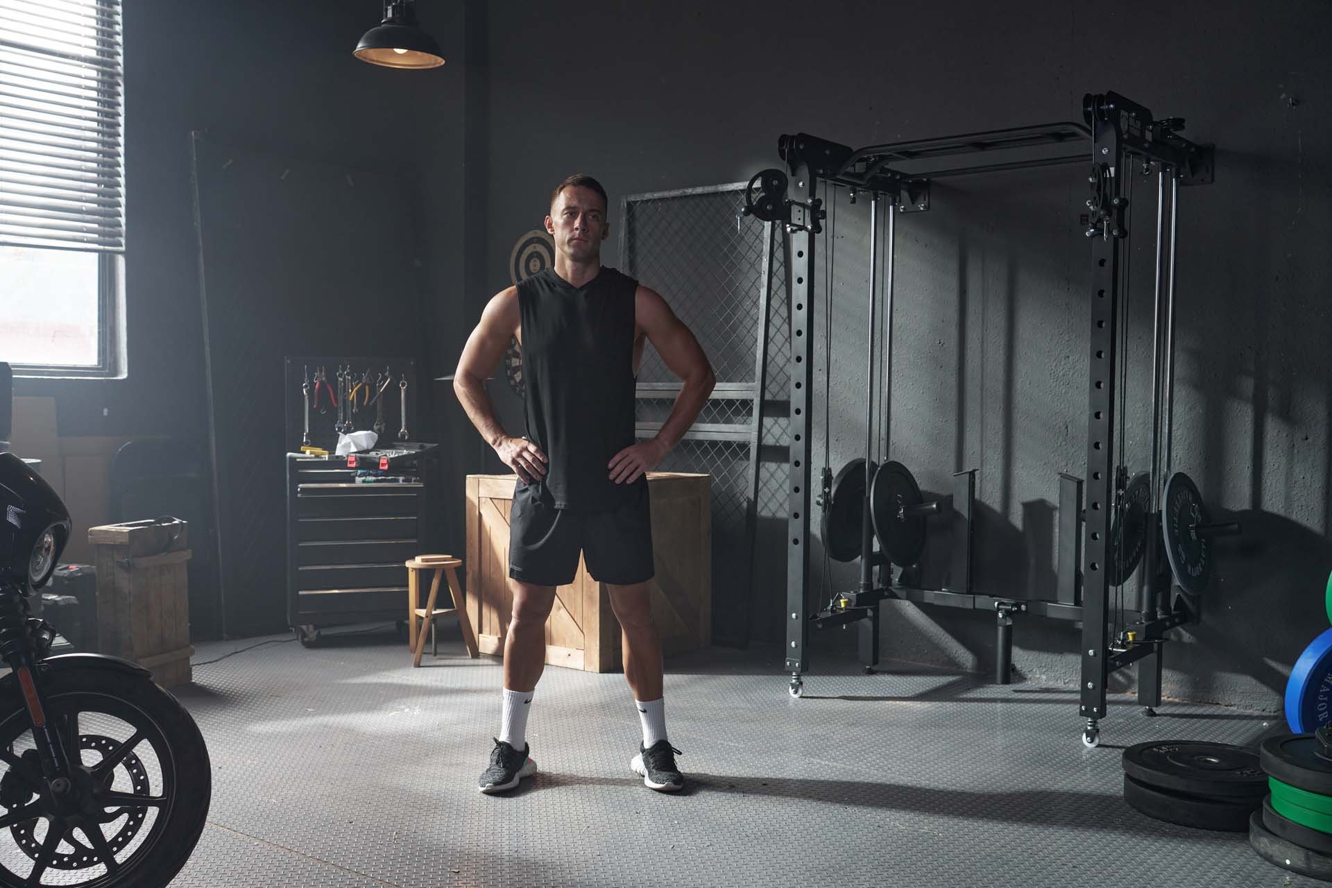 A man stands in a well-equipped home garage gym
