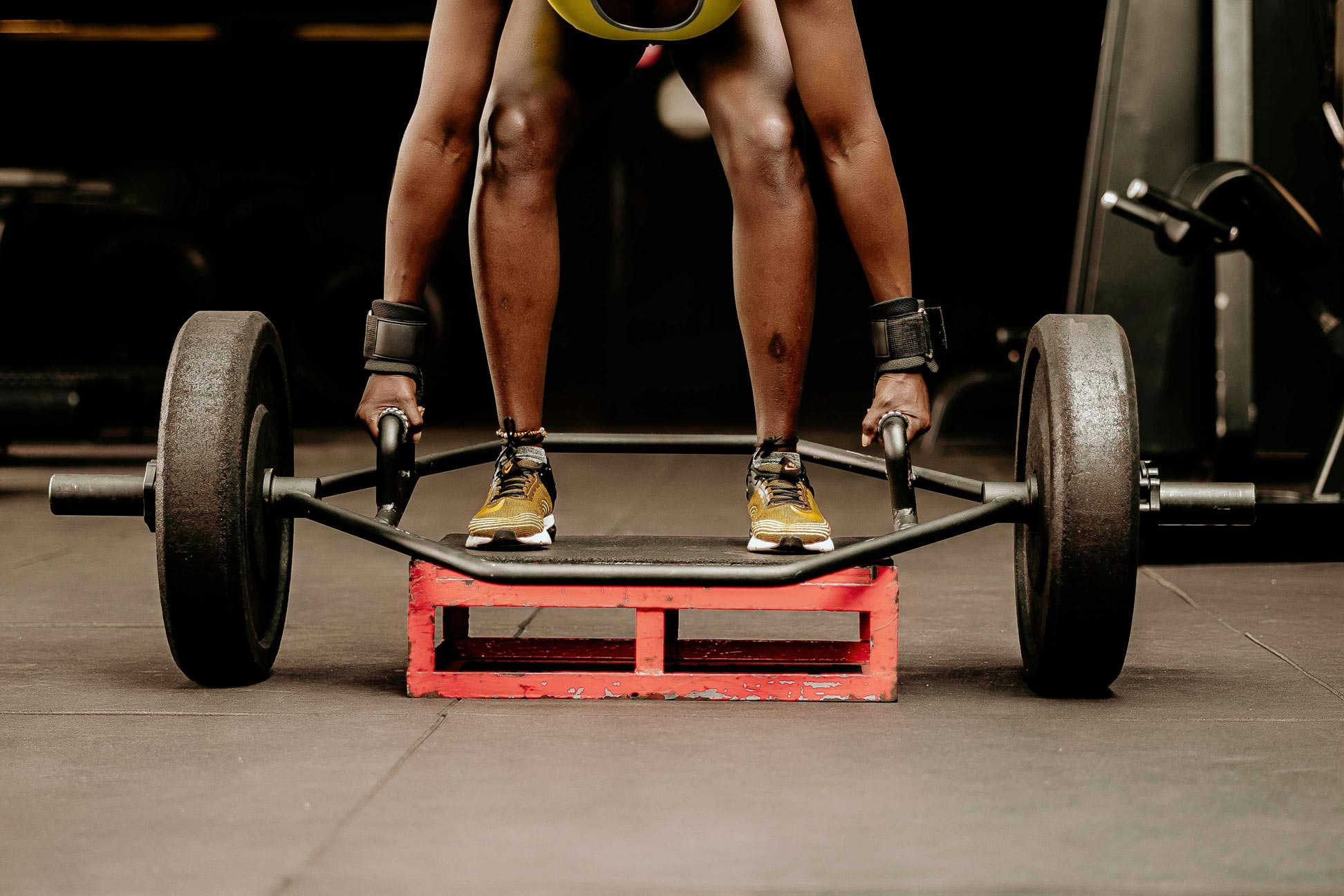 Fitness enthusiast performing deadlifts with a hexagonal trap bar on a red platform, in a well-equipped home gym setting