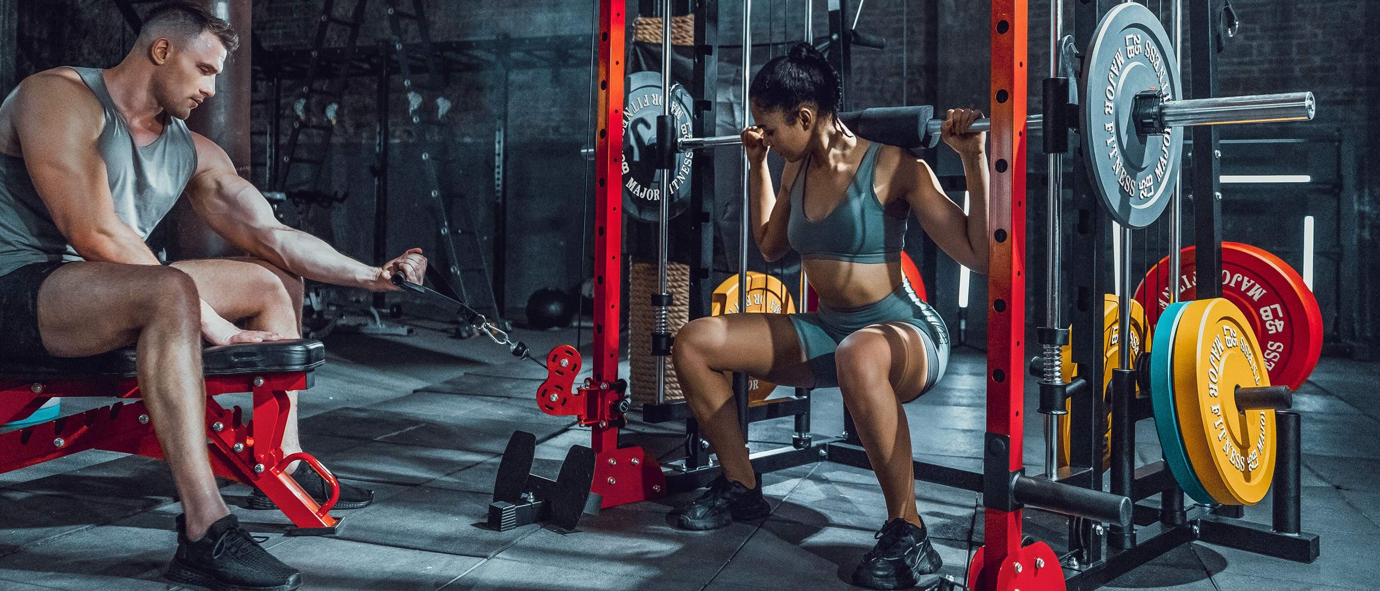 a man using a rowing machine and a woman squatting at a gym