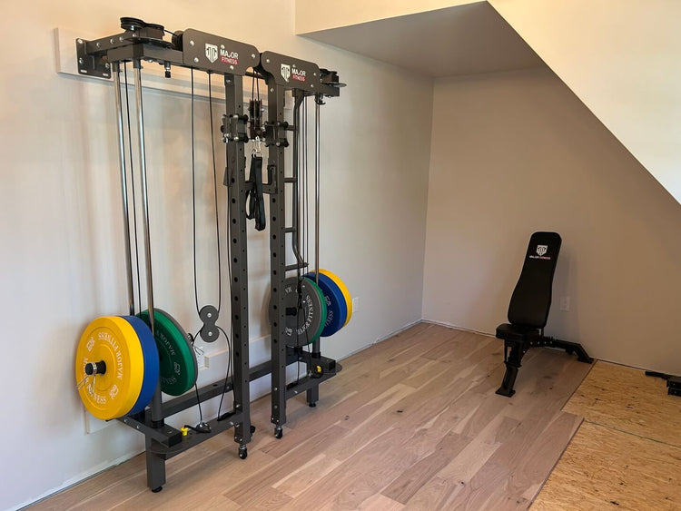 home gym featuring a cable machine, colorful Olympic weight plates, and an adjustable workout bench in a well-lit room with wooden floors