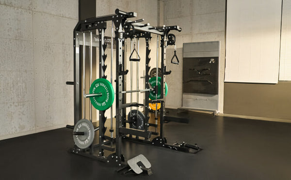 multi-station home gym setup featuring a Smith machine and power rack system, complete with multiple cable pulleys, weight plate storage, and green and grey Olympic weight plates