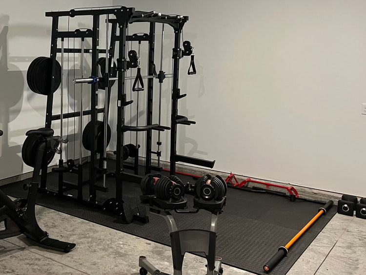 home gym setup featuring a cable machine, adjustable workout bench, weight plates, and various strength training accessories on a rubber mat