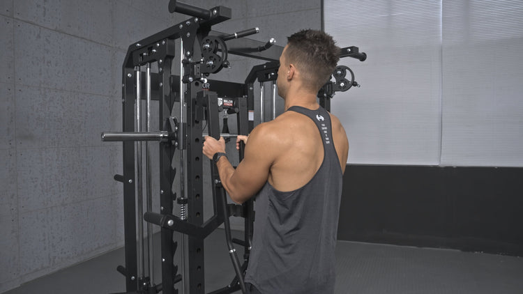 Man installing a shoulder lateral raise on a gym machine