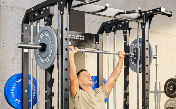 Fit man engaged in an overhead press exercise using a Smith machine